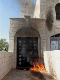 Flames are seen at the entrance of an Anglican church hit by a firebomb in Nablus. Photo: AP
